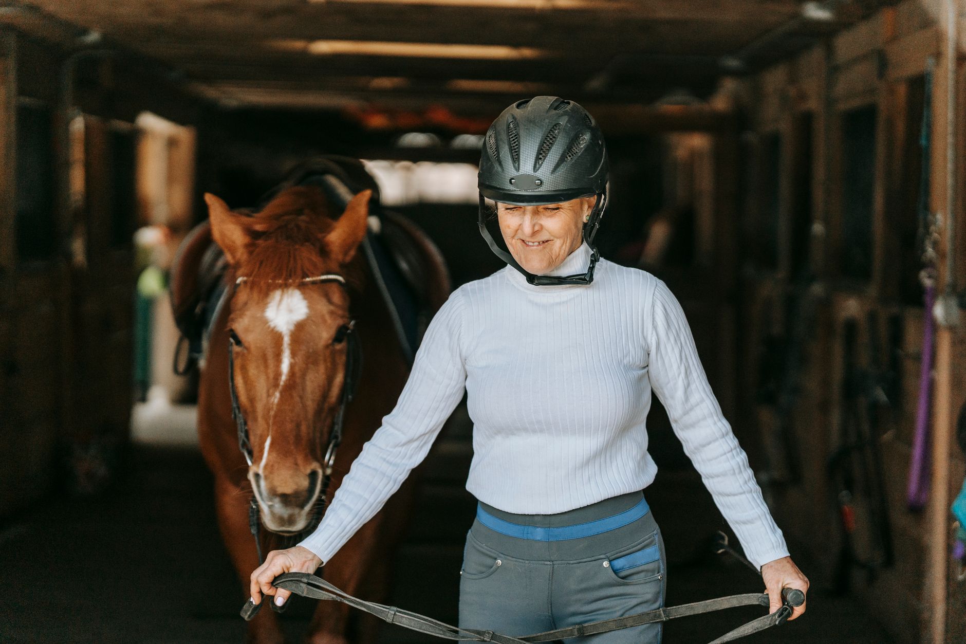 Woman leading horse in stable
